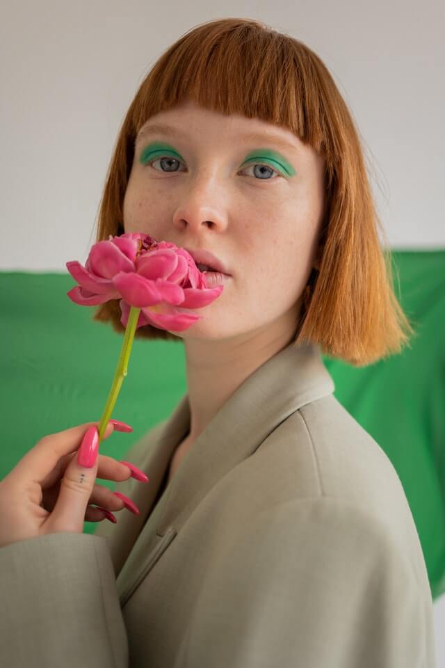Female model with flower in front of face - benefits of plant based makeup concept